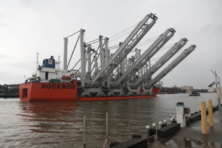 A heavy-lift vessel carrying four ship-to-shore container cranes on deck